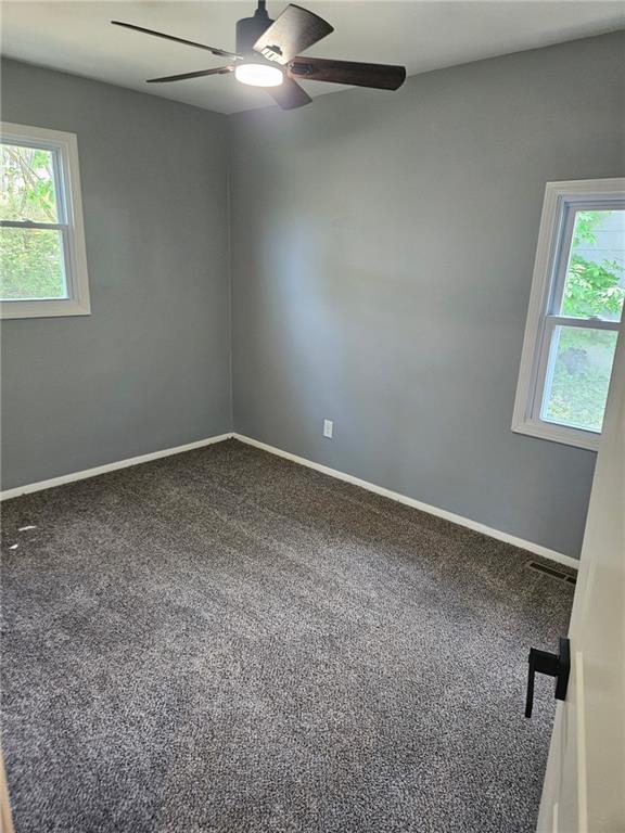 4715 E 45th St, Kansas City, MO 64130 - carpeted empty room with ceiling fan, plenty of natural light, and baseboards