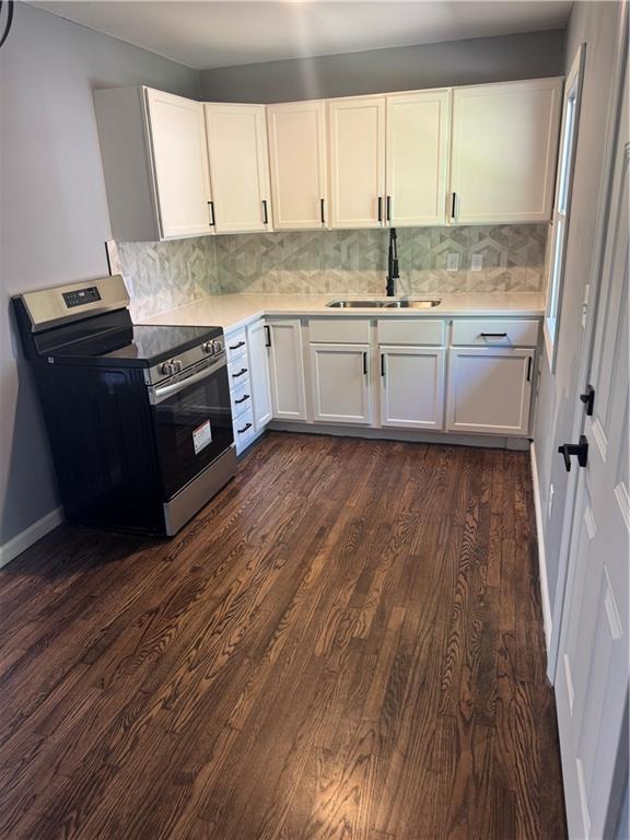4715 E 45th St, Kansas City, MO 64130 - kitchen with stainless steel electric range oven, a sink, dark wood-style floors, light countertops, and backsplash