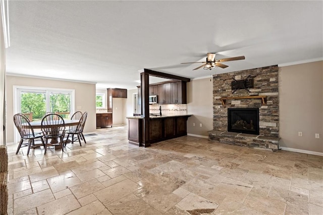 21815 W 73rd Ter, Shawnee, KS 66218 - living area featuring stone tile floors, a ceiling fan, crown molding, a stone fireplace, and baseboards