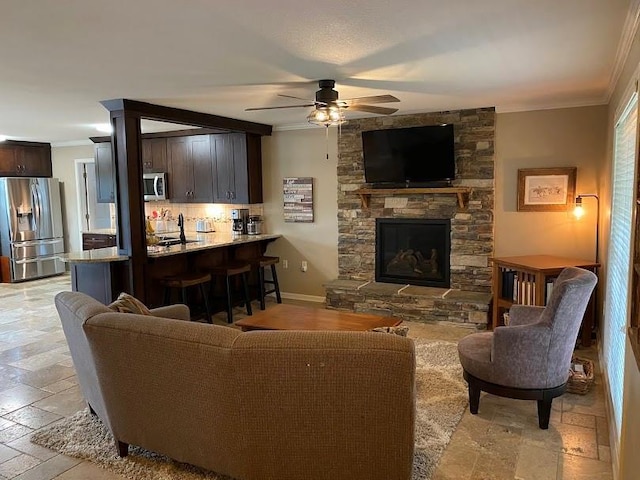 21815 W 73rd Ter, Shawnee, KS 66218 - living room with crown molding, ceiling fan, stone tile flooring, a stone fireplace, and baseboards