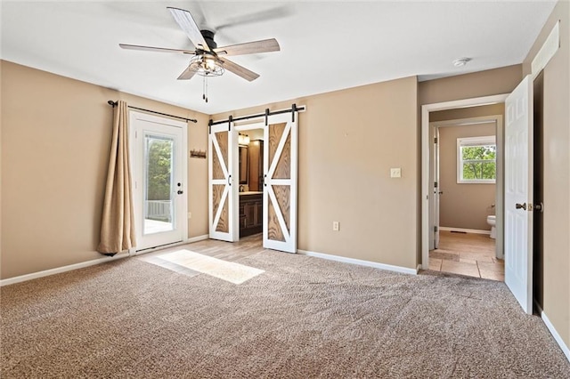 21815 W 73rd Ter, Shawnee, KS 66218 - unfurnished bedroom featuring access to exterior, light colored carpet, a barn door, and ensuite bathroom