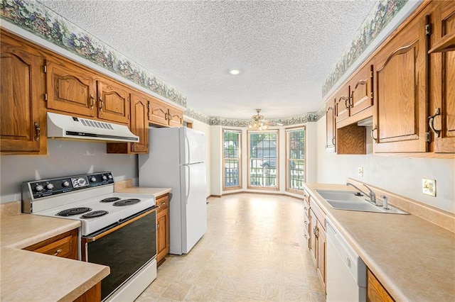 kitchen with white appliances, under cabinet range hood, a textured ceiling, light countertops, and a sink
