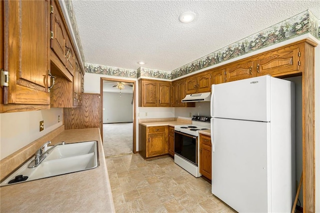 kitchen featuring white appliances, range hood, a sink, a textured ceiling, and brown cabinets