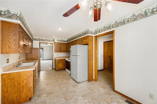 kitchen with white appliances, a ceiling fan, light countertops, a textured ceiling, and a sink