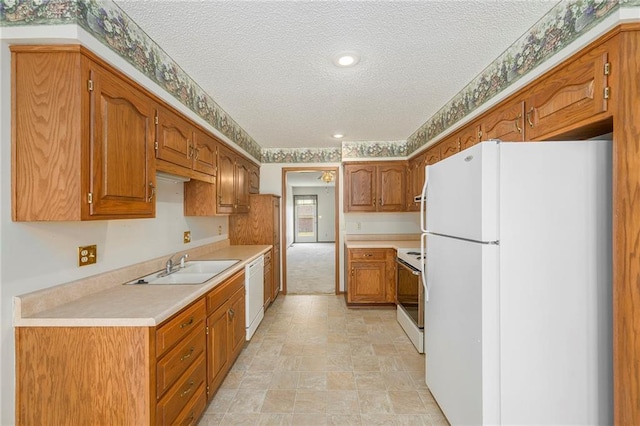 kitchen with white appliances, a textured ceiling, a sink, light countertops, and brown cabinets
