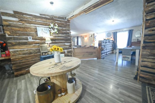 dining space featuring a textured ceiling, wood finished floors, and rustic walls