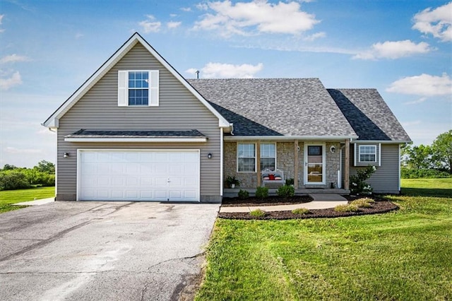 traditional-style house featuring driveway, a front yard, a shingled roof, and stone siding