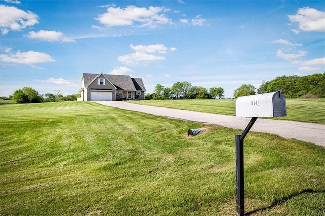 view of front of home with driveway, an attached garage, a front yard, and a view of countryside