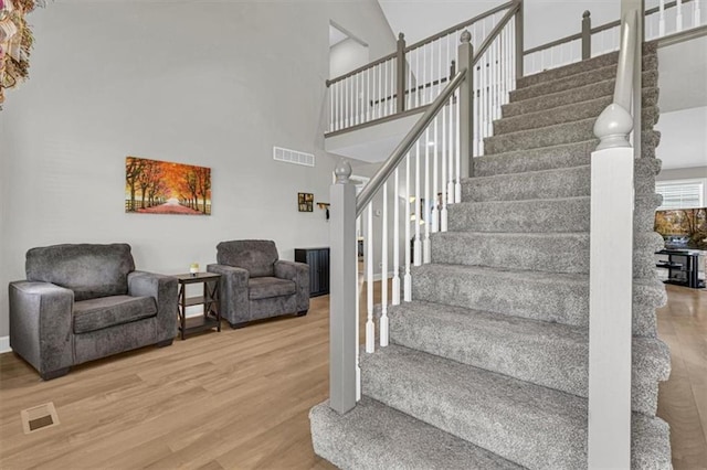 stairs featuring wood finished floors and a high ceiling
