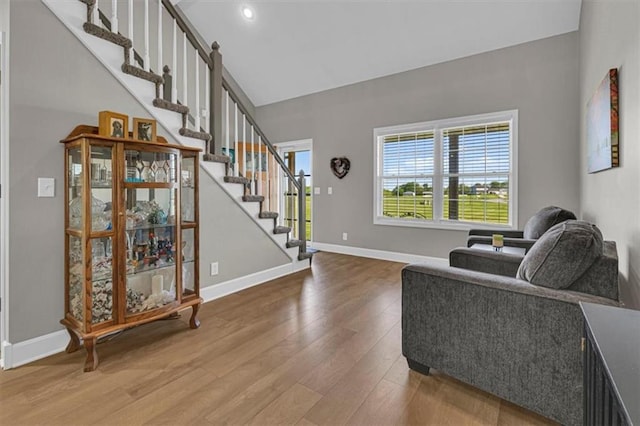 living area featuring wood finished floors, stairway, baseboards, and vaulted ceiling