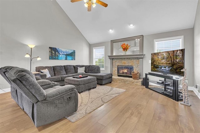 living room with wood finished floors, a ceiling fan, a fireplace, high vaulted ceiling, and baseboards