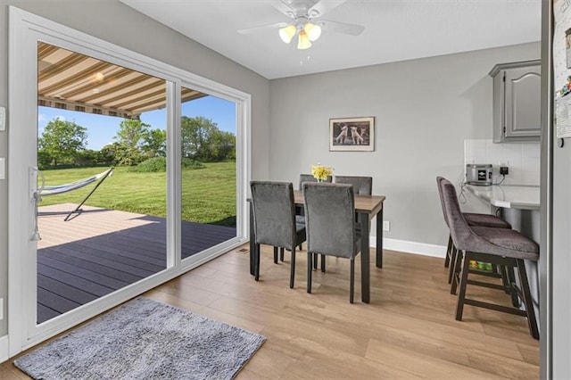 dining space with a ceiling fan, light wood-style flooring, and baseboards