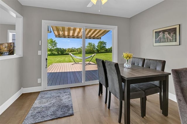 dining space featuring wood finished floors, baseboards, and a ceiling fan