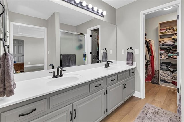bathroom with double vanity, a shower stall, and a spacious closet