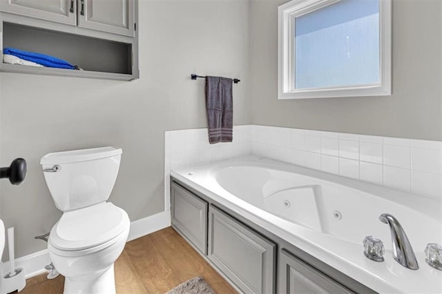 bathroom featuring toilet, a jetted tub, and wood finished floors
