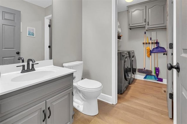 bathroom with washer and dryer, toilet, wood finished floors, vanity, and baseboards