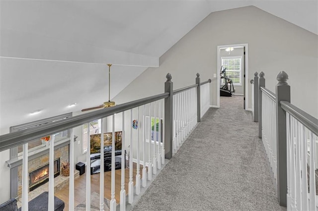 hall featuring vaulted ceiling, an upstairs landing, and carpet flooring