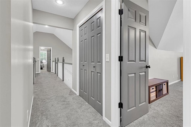 corridor featuring carpet flooring, lofted ceiling, and baseboards