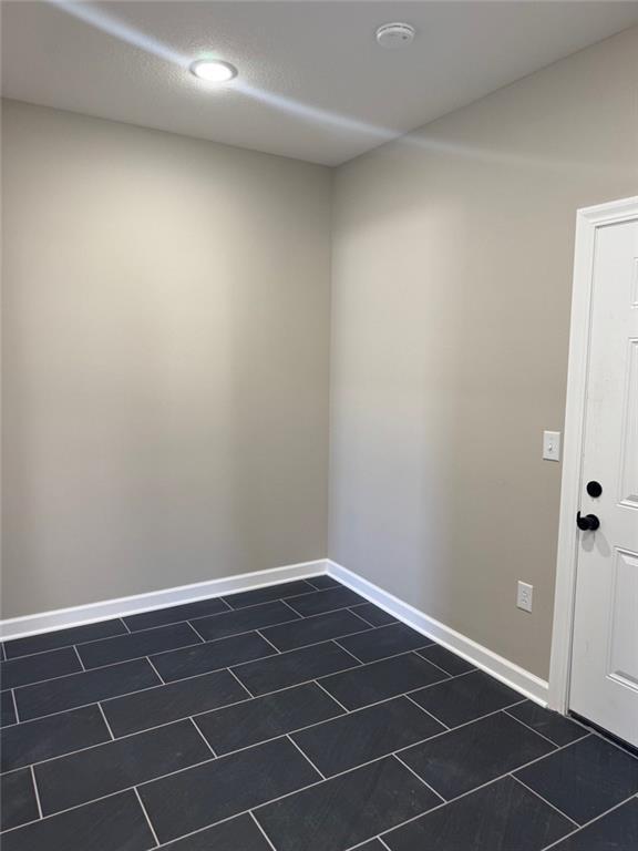 305 N Prairie St, Hamilton, MO 64644 - unfurnished room featuring dark tile patterned flooring and baseboards