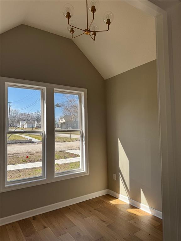 305 N Prairie St, Hamilton, MO 64644 - unfurnished room featuring plenty of natural light, a chandelier, wood finished floors, lofted ceiling, and baseboards
