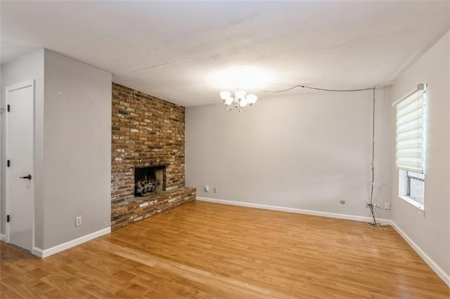 unfurnished living room with light wood-style flooring, a chandelier, and baseboards