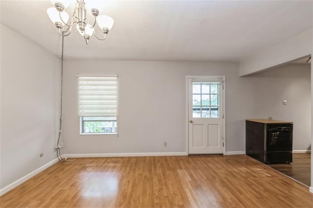 unfurnished dining area featuring light wood finished floors, a chandelier, and baseboards