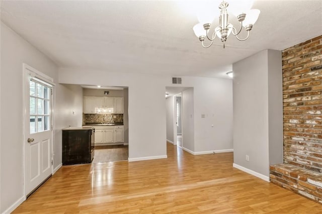 unfurnished living room with light wood-style floors, a chandelier, and baseboards