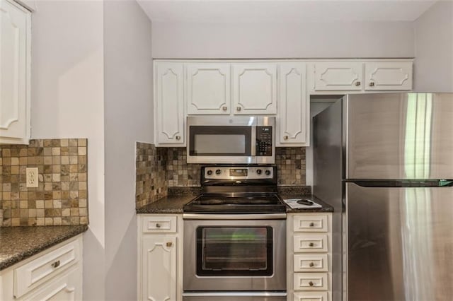 kitchen with stainless steel appliances, decorative backsplash, white cabinets, and dark stone countertops