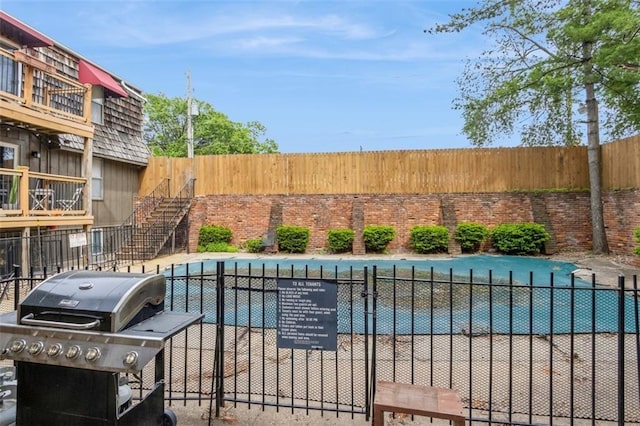 view of swimming pool with fence, a pool, and grilling area