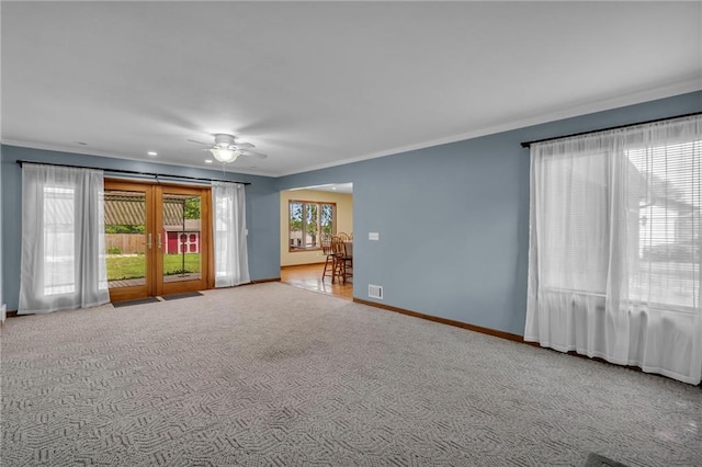 carpeted empty room featuring crown molding, a ceiling fan, and baseboards