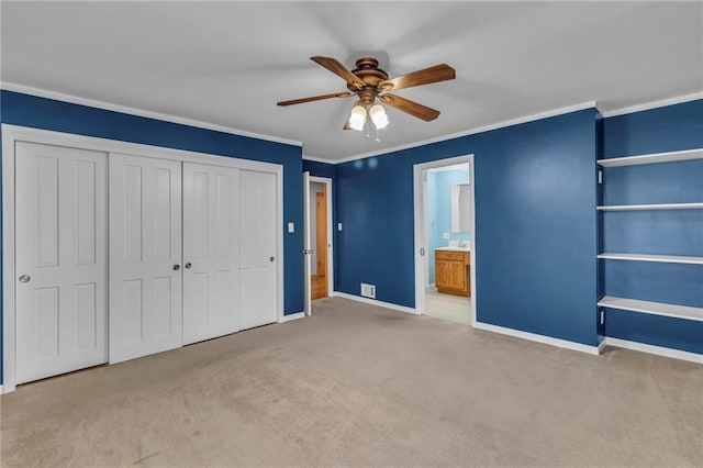 unfurnished bedroom with baseboards, a closet, carpet floors, ornamental molding, and a ceiling fan