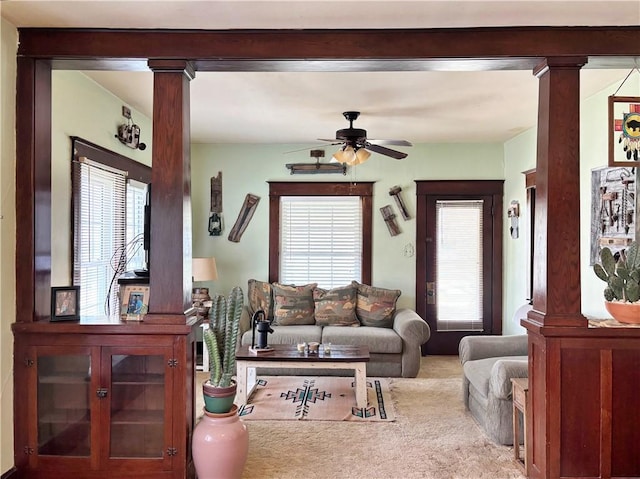living area featuring ornate columns, a ceiling fan, and carpet
