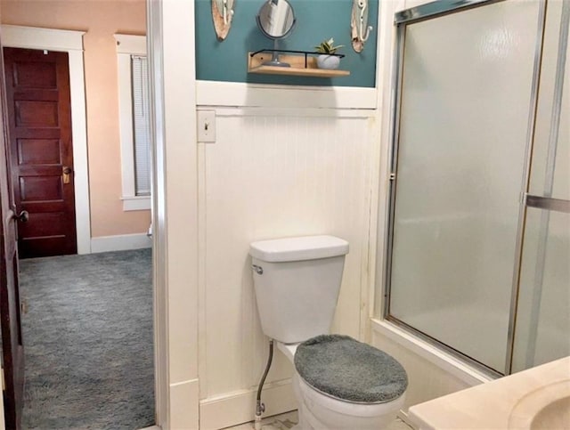 full bath with a wainscoted wall, a stall shower, toilet, vanity, and baseboards