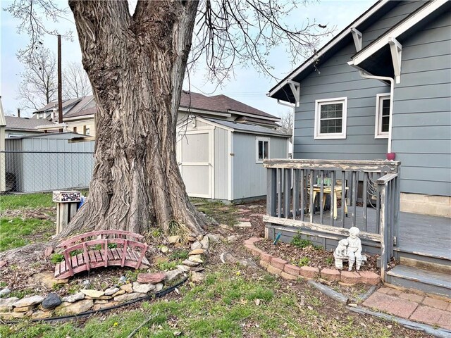 view of yard featuring a shed, a wooden deck, an outbuilding, and fence