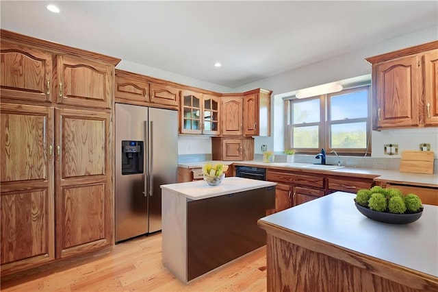 kitchen featuring high quality fridge, a sink, light countertops, light wood-type flooring, and recessed lighting