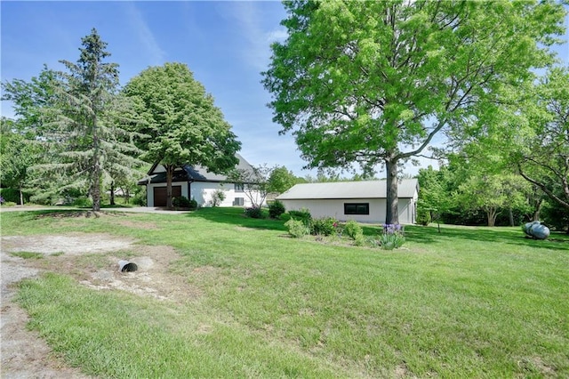 view of green lawn featuring a garage and an outbuilding