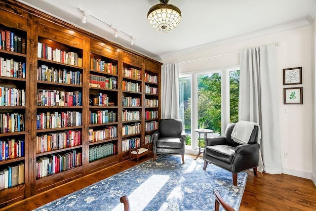 7711 N Montgall Ave, Kansas City, MO 64119 - sitting room featuring wall of books, baseboards, ornamental molding, and wood finished floors