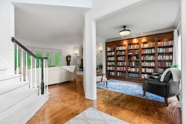 7711 N Montgall Ave, Kansas City, MO 64119 - sitting room with ornamental molding, bookshelves, wood finished floors, and stairs