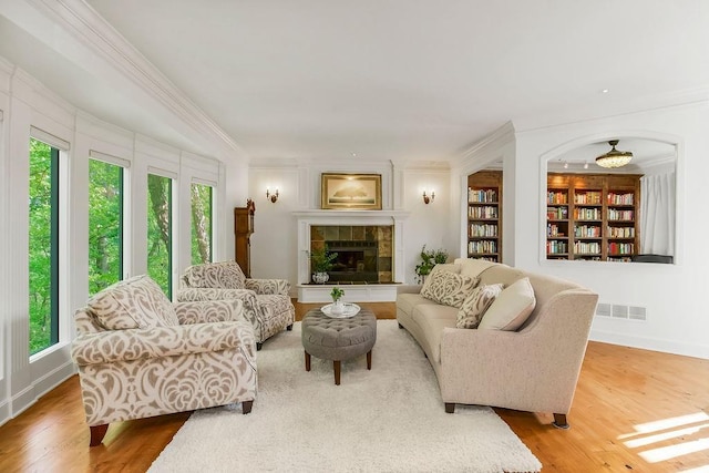 7711 N Montgall Ave, Kansas City, MO 64119 - living room featuring ornamental molding, wood finished floors, built in shelves, baseboards, and a tiled fireplace