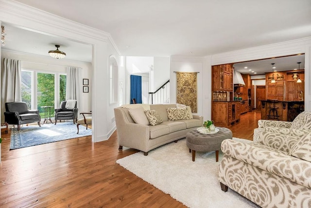 7711 N Montgall Ave, Kansas City, MO 64119 - living room featuring wood finished floors, crown molding, baseboards, and stairs