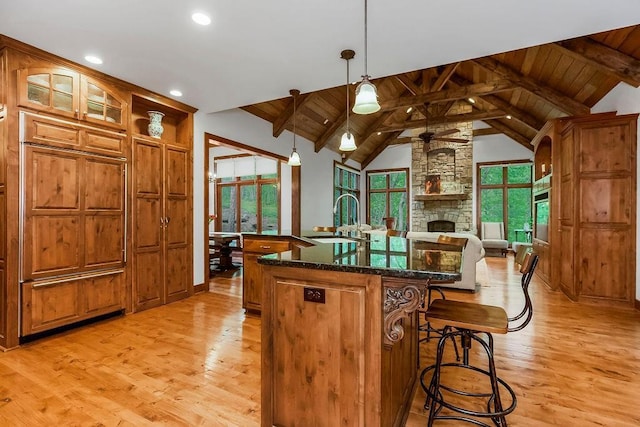 7711 N Montgall Ave, Kansas City, MO 64119 - kitchen featuring light wood finished floors, a sink, an island with sink, a breakfast bar, and brown cabinets