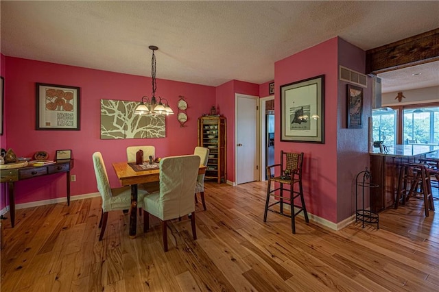 537 NE State Route 13th Hwy, Warrensburg, MO 64093 - dining space with hardwood / wood-style floors, a textured ceiling, a chandelier, and baseboards