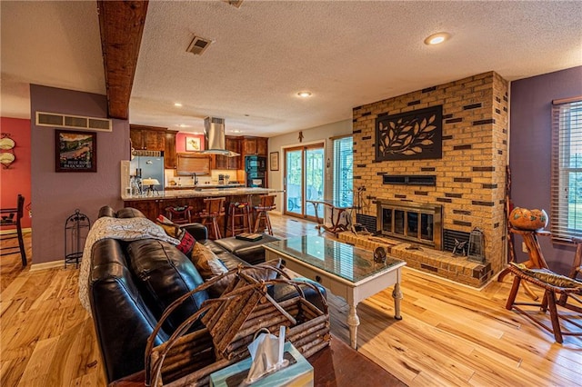 537 NE State Route 13th Hwy, Warrensburg, MO 64093 - living area featuring a textured ceiling, light wood-style flooring, a brick fireplace, recessed lighting, and baseboards