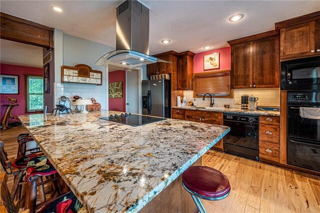 537 NE State Route 13th Hwy, Warrensburg, MO 64093 - kitchen featuring black appliances, island range hood, a kitchen breakfast bar, light wood finished floors, and backsplash