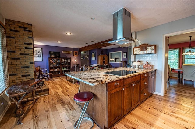 537 NE State Route 13th Hwy, Warrensburg, MO 64093 - kitchen featuring black electric cooktop, light wood-type flooring, a peninsula, light stone counters, and island exhaust hood