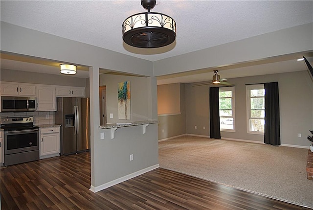 1748 NE Ridgeview Dr, Lees Summit, MO 64086 - kitchen with appliances with stainless steel finishes, white cabinets, dark wood-style flooring, light stone counters, and open floor plan