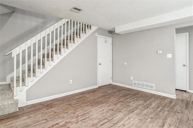 5516 66th Ter, Kansas City, MO 64151 - unfurnished living room with wood finished floors, a textured ceiling, stairs, and baseboards