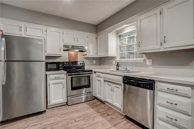 5516 66th Ter, Kansas City, MO 64151 - kitchen featuring appliances with stainless steel finishes, under cabinet range hood, white cabinetry, light countertops, and a textured ceiling