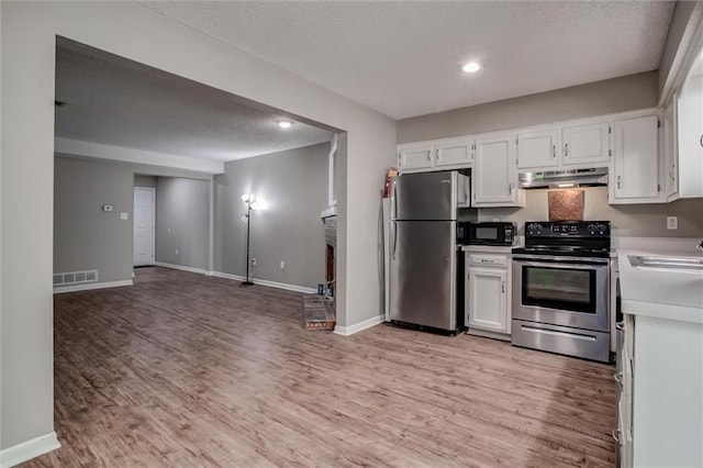 5516 66th Ter, Kansas City, MO 64151 - kitchen with stainless steel appliances, under cabinet range hood, light countertops, light wood-style floors, and white cabinetry