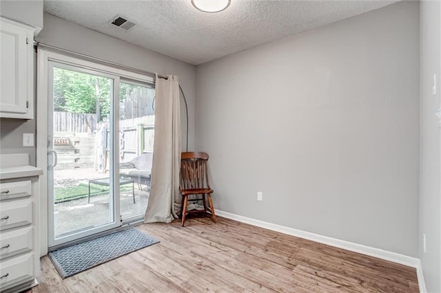 5516 66th Ter, Kansas City, MO 64151 - doorway with a textured ceiling, light wood-type flooring, and baseboards